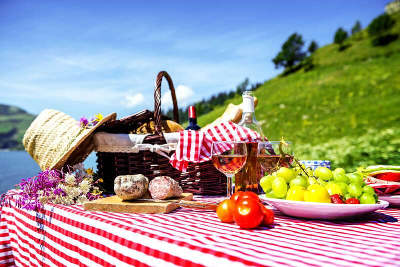 Picnic basket and wine on the grass near a lake Girls Who Travel | 5 Picnic Tips For A Perfect Day Out
